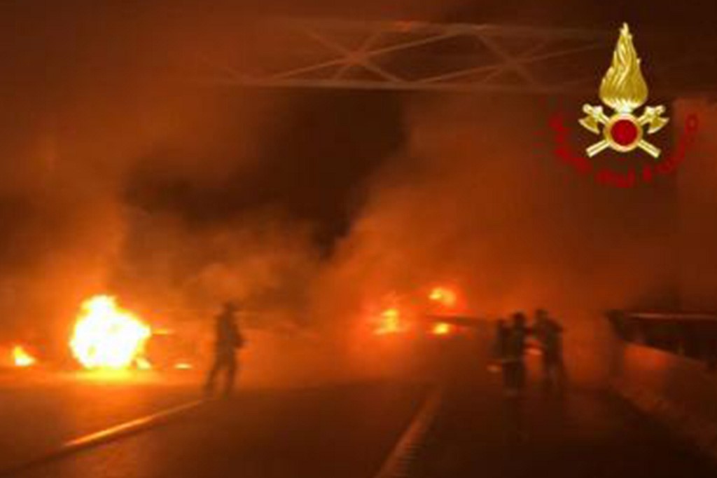 This photo taken and handout on January 29, 2020 by the Italian Department of firefighters, the Vigili del Fuoco, shows rescuers intervening after criminals attempted to ambush an armoured truck on a stretch of highway between Milan and Lodi, in San Zenone al Lambro. - Several burning vehicles on a highway in northern Italy were set up to stop an armored truck carrying cash, but the truck's driver managed to drive through the wall of fire and escape. The attack occurred shortly before midnight late on January 28, 2020, as criminals set fire to about ten vehicles, all probably stolen, in both directions of travel on the motorway. (Photo by Handout / various sources / AFP) / RESTRICTED TO EDITORIAL USE - MANDATORY CREDIT 